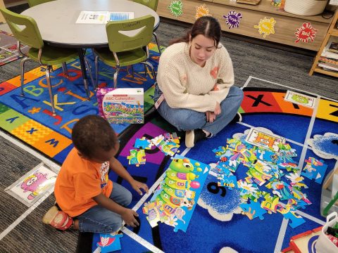 teacher and child sitting on play mat
